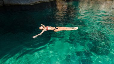 Bir kadın turkuvaz kıyı sularında huzur içinde yüzmekten hoşlanır.. 