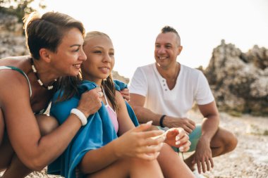 Anne kızını kucaklarken neşeli aile sahilde birlikte eğleniyor.. 