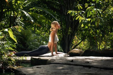 Tropik ortamda yoga yapan genç bir kadının portresi