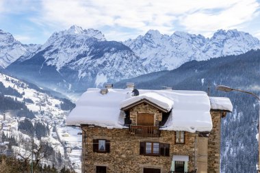 İsviçre Alpleri kışın ön planda taş bina ve arka planda köy ile