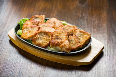 Dökme demir bir tepside güzel kızarmış domuz eti parçaları ve marul parçaları.