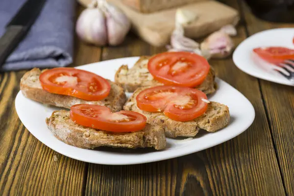 마늘과 토마토 조각으로 퍼지는 올리브 오일의 토스트 로열티 프리 스톡 사진