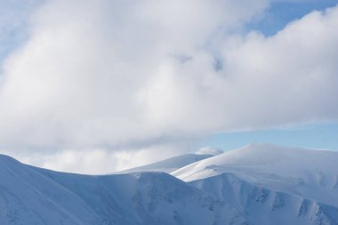 Karlı dağ sırtları Alp Dağları 'ndaki dramatik bulutların altında manzaralı bir kış manzarası
