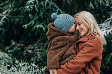 Anne ve oğlu kışın karlı bahçede ladin yakınlarında, Polonya