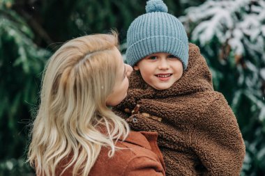 Anne ve oğlu kışın karlı bahçede ladin yakınlarında, Polonya
