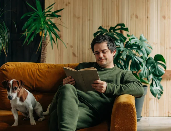 Caucasian Man Book Dog Sits Sofa Home — Zdjęcie stockowe