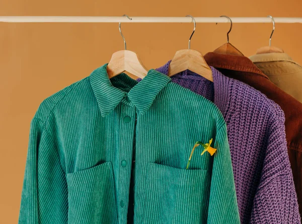 stylish colored shirts on hangers on a brown background
