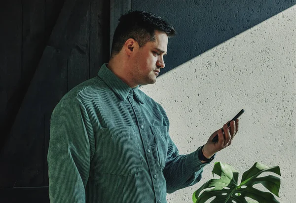 Caucasian Guy Green Shirt Looking Display Smartphone Home Whadow Wall — Foto de Stock