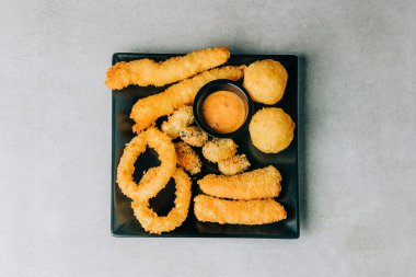 Kızarmış kalamar ve siyah tabakta balıkla yükseliş. 