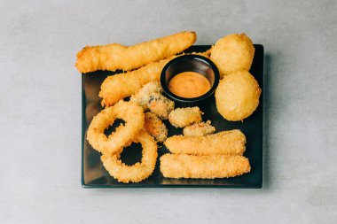 Kızarmış kalamar ve siyah tabakta balıkla yükseliş. 