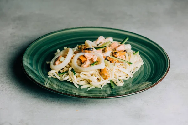 stock image Noodles with calmari tuna and cucumber on green plate