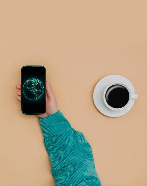 ノートの横にスマートフォンを持ち 茶色の背景にコーヒーのカップを持つ女性の手の上のPovビュー ロイヤリティフリーのストック写真