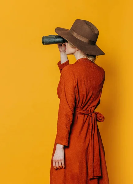 Sarı Arka Planda Dürbünü Olan Kahverengi Elbiseli Şık Bir Kadın — Stok fotoğraf