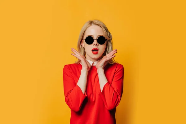 Kırmızı Elbiseli Sarı Arka Planda Güneş Gözlüklü Ciddi Sarışın Kadın — Stok fotoğraf