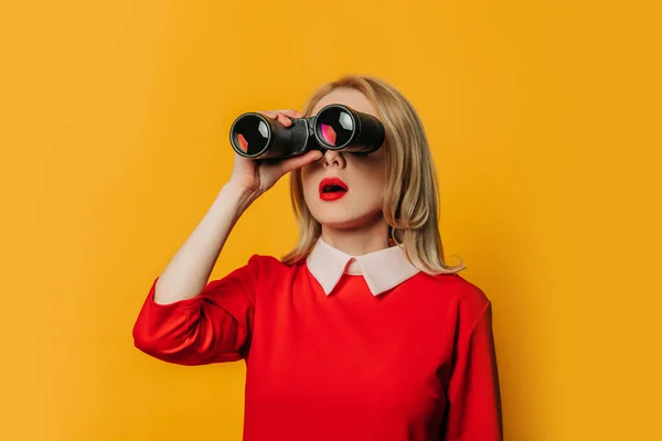 Überraschte Blonde Haarfrau Rotem Kleid Mit Fernglas Auf Gelbem Hintergrund — Stockfoto