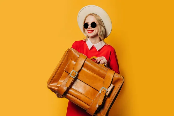 Sarı Arka Planda Bavulu Olan Kırmızı Elbiseli Gülümseyen Sarışın Kadın — Stok fotoğraf