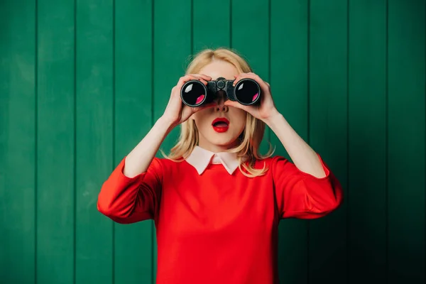 Überraschte Blonde Haarfrau Rotem Kleid Mit Fernglas Auf Grünem Holzgrund — Stockfoto