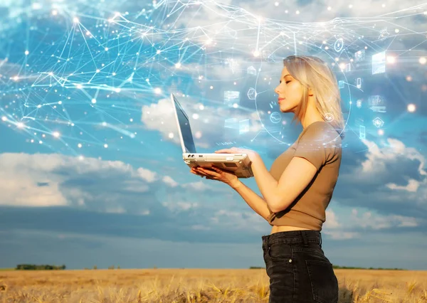 Blonde woman with laptop computer and abstract connections in wheat field in summer time