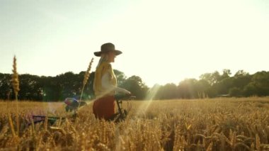 Altın buğday tarlasında şık giyinmiş, şapkalı, şık bir kadın.