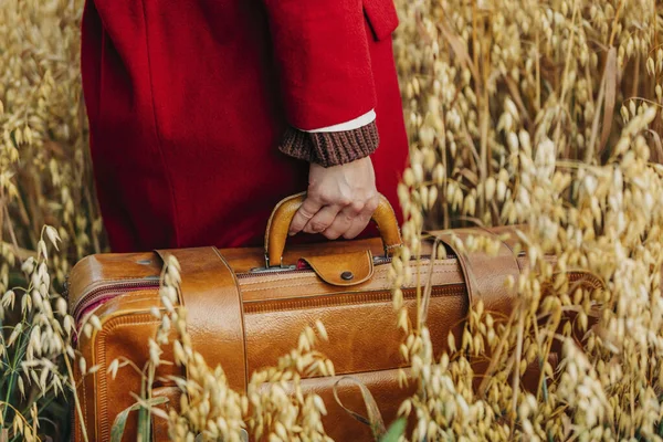 燕麦田里穿着红色外套的女人拿着老式手提箱的服装形象 — 图库照片