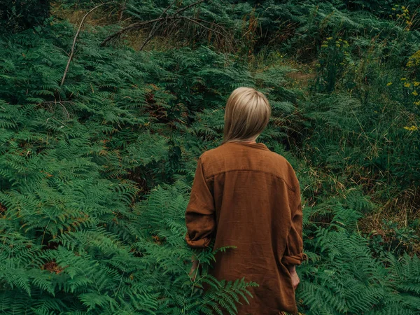 女性は森の中のフェルンと松の木の間に立っています ロイヤリティフリーのストック写真