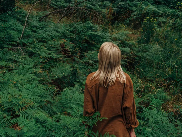 女性は森の中のフェルンと松の木の間に立っています ロイヤリティフリーのストック画像