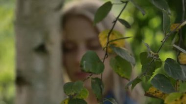 Sonbahar mevsiminde köyde huş ağacına sarılan kadın.