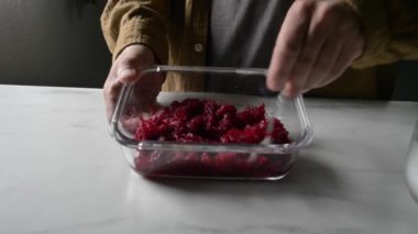 Adam mutfakta cam kapta kaynamış pancarla susam tohumunu karıştırıyor.