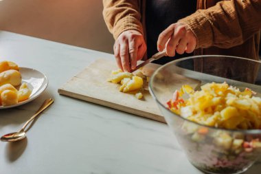 Adam mutfakta salata için patates kesiyor.