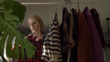Avrupalı bir kadın internetten giysi satmak için kıyafetlerini seçiyor.