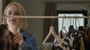 Avrupalı bir kadın internetten giysi satmak için kıyafetlerini seçiyor.