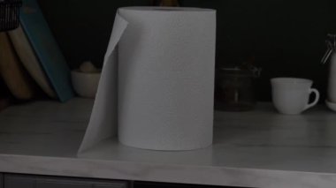 Mutfak masasındaki kağıt havluların yakın plan çekimi. Adamın biri elini uzattı, çarşafı yırttı ve ellerini silmek için kullandı..