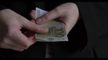 Avro banknotlarıyla el ele tutuşurken, bir adam her seferinde bir banknotu yığından atıyor.