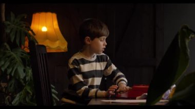 Okul çağındaki genç bir çocuk sıcak bir yuva ortamında ailesinin klasik daktilosuyla oynuyor.