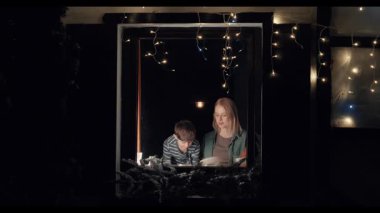 Akşamları beyaz anne ve oğlu mutfak penceresinin önünde birlikte bulaşıkları yıkıyor ve kurutuyorlar. Dışarıdan görülüyorlar.