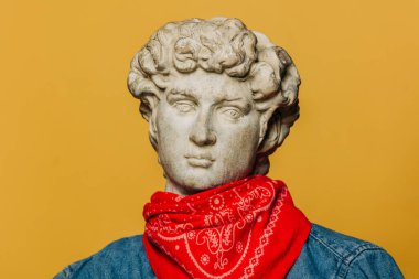 Kırmızı hippi şapkalı ve sarı arka planda bandanalı kovboy gömlekli bir gencin antik heykeli.