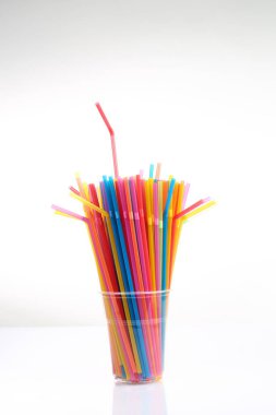 Beyaz bir fincanda renkli plastik pipetler