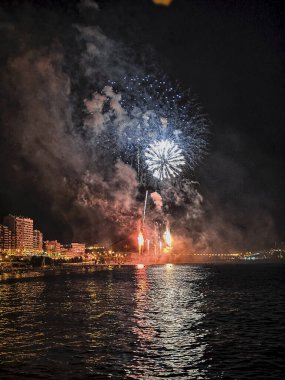 Alicante İspanya 'nın deniz kenarında gece gökyüzünde güzel renkli havai fişekler.