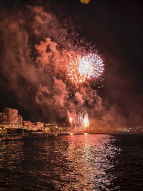 Alicante İspanya 'nın deniz kenarında gece gökyüzünde güzel renkli havai fişekler.