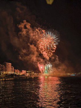 Alicante İspanya 'nın deniz kenarında gece gökyüzünde güzel renkli havai fişekler.