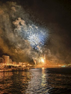 Alicante İspanya 'nın deniz kenarında gece gökyüzünde güzel renkli havai fişekler.