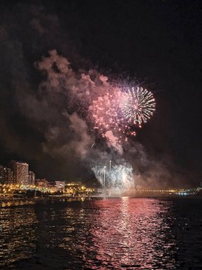 Alicante İspanya 'nın deniz kenarında gece gökyüzünde güzel renkli havai fişekler.