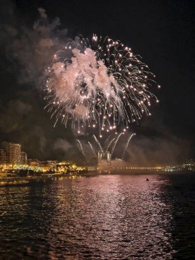 Alicante İspanya 'nın deniz kenarında gece gökyüzünde güzel renkli havai fişekler.