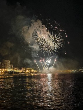 Alicante İspanya 'nın deniz kenarında gece gökyüzünde güzel renkli havai fişekler.