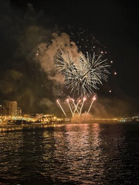 Alicante İspanya 'nın deniz kenarında gece gökyüzünde güzel renkli havai fişekler.