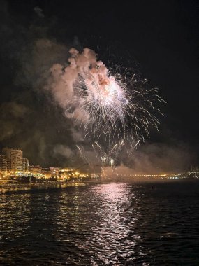 Alicante İspanya 'nın deniz kenarında gece gökyüzünde güzel renkli havai fişekler.