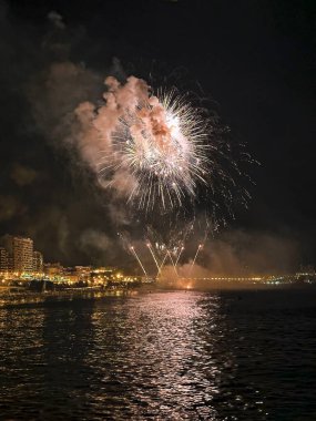 Alicante İspanya 'nın deniz kenarında gece gökyüzünde güzel renkli havai fişekler.