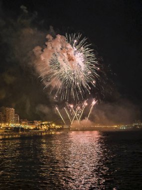 Alicante İspanya 'nın deniz kenarında gece gökyüzünde güzel renkli havai fişekler.
