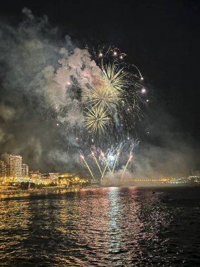 Alicante İspanya 'nın deniz kenarında gece gökyüzünde güzel renkli havai fişekler.