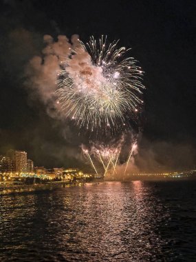 Alicante İspanya 'nın deniz kenarında gece gökyüzünde güzel renkli havai fişekler.